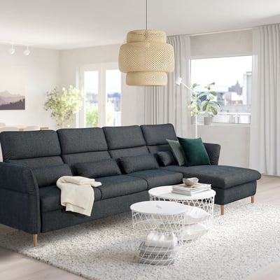 Modern living room with grey sofa, green pillows, white table, and large beige lamp.