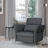 Dark gray FAMMARP armchair in cozy room next to table with plant and cup. Adjustable head and armrests.