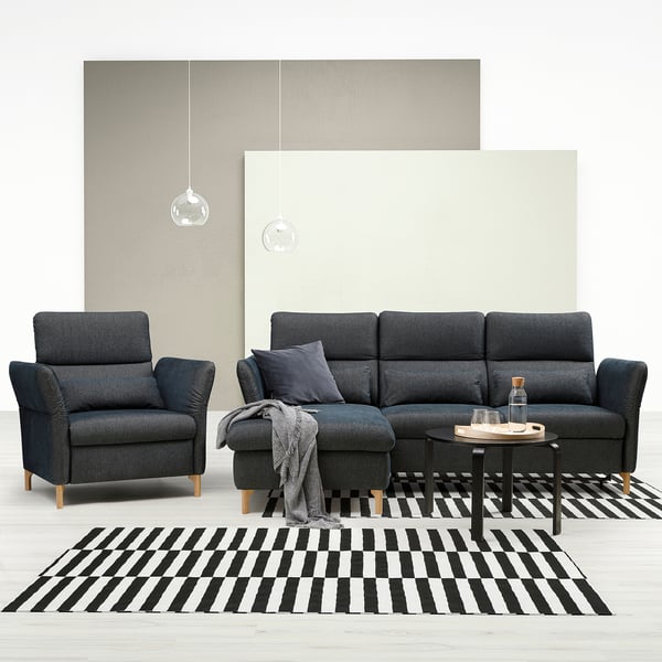 Modern living room with dark grey FAMMARP sofa & chair, black & white striped rug, grey armchair, and minimalist pendant lamps.
