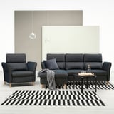 Modern living room with dark grey FAMMARP sofa & chair, black & white striped rug, grey armchair, and minimalist pendant lamps.