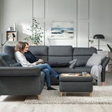 Two people relax on FAMMARP sectional sofa in modern living room.