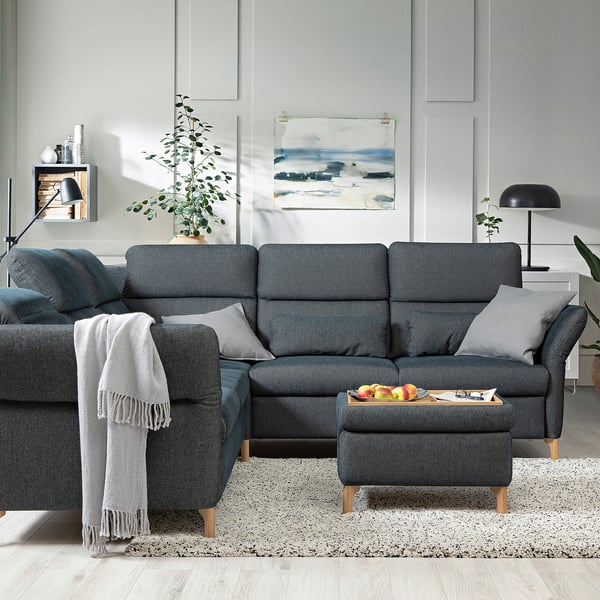 Grey l-shape sofa with pillows, rug, painting, lamp, plant.