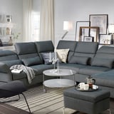 Modern living room with dark grey FAMMARP sectional sofa, glass coffee table, and stylish decorations.