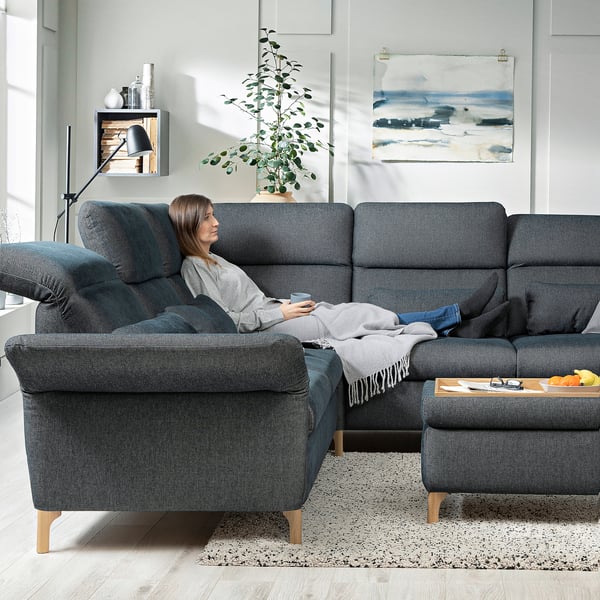 Woman relaxes on dark blue FAMMARP sectional sofa, grey throw, modern living room.
