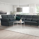 Modern living room with dark grey l-shaped FAMMARP sofa, green cushions, white coffee table, large windows, and stylish hanging lamp.