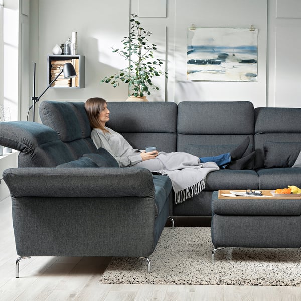 A modern, gray-blue FAMMARP sectional sofa with adjustable headrests and armrests in a cozy living room with a plant and abstract art on the walls.