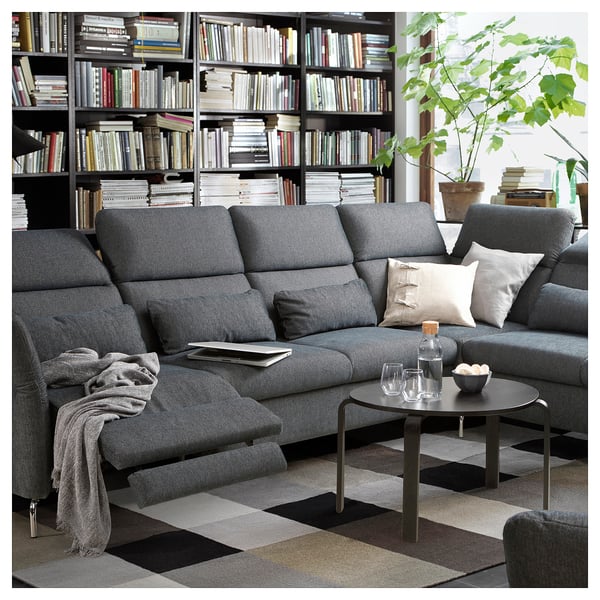 Modern grey l-shaped FAMMARP sofa with adjustable headrests and pillows, set against a large bookshelf and a potted plant.