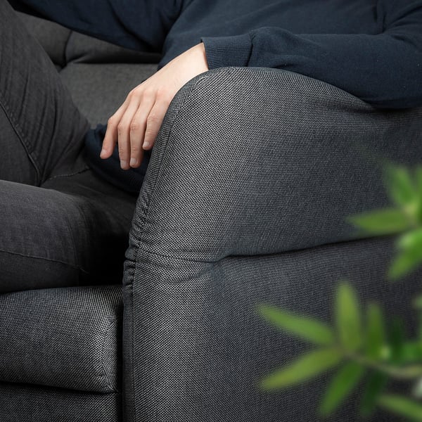 Person resting on FAMMARP sofa with modern, adjustable design.
