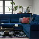 Modern living room with FAMMARP blue velvet sectional sofa, colorful pillows, patterned rug, and black coffee table.