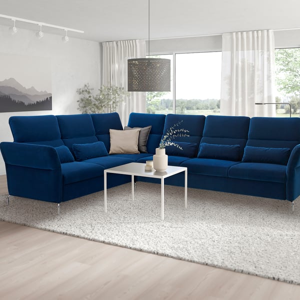 Modern blue velvet sectional sofa in spacious living room, luxurious comfort & adjustable support.