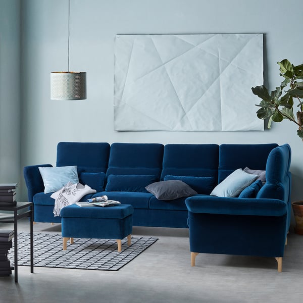 Modern living room with blue FAMMARP sectionals. Velvet fabric, adjustable headrests, geometric art, grey rug.