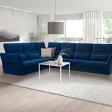 Modern living room with large blue FAMMARP sectional sofa, white coffee table, sleek lamp, and neutral rug.