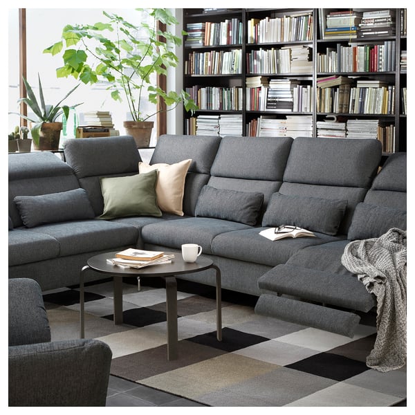 Modern living room with gray FAMMARP sectional sofa, black coffee table, colorful rug, and bookshelf filled with books.