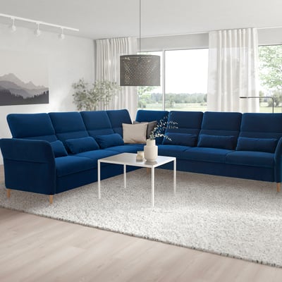 Modern living room with blue sectional sofa, white coffee table, and large windows.