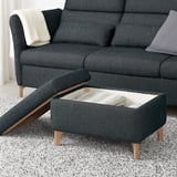 Dark grey sofa with adjustable headrests, lumbar support, and a matching footstool featuring storage under the seat, placed on a speckled rug.