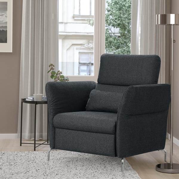 Dark gray FAMMARP recliner near window. Comfortable, high resilience foam, chic design. Smaller than side lamp, larger than plant.