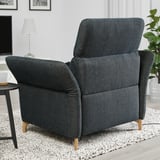 Dark gray FAMMARP recliner in living room, large, wood legs, plush, against white wall, near small table.
