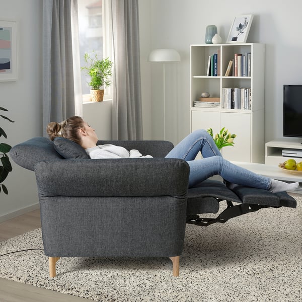 Woman relaxing in FAMMARP recliner, adjustable sofa, books, lamp, big window.