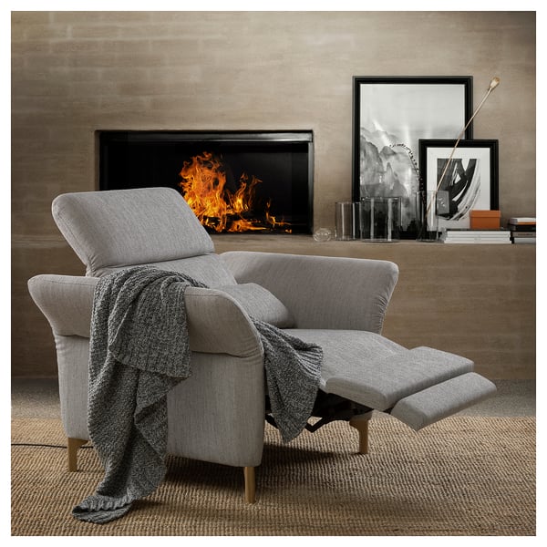 Cozy living room with gray FAMMARP recliner by fireplace, cushioned for comfort, paired with textured rug and modern decor.