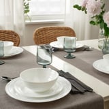 FAVORISERA dinnerware set on gray tablecloth, vase of pink flowers.