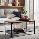 Modern living room with white sofa, industrial-style black metal and wooden coffee table, topped with a potted plant.
