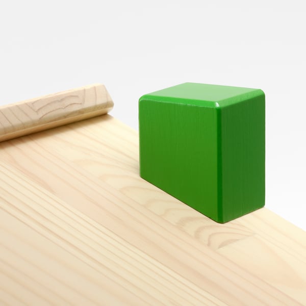 A green square block sits on a light wooden table, showing quality craftsmanship with smooth surfaces and clean lines.