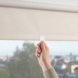 Hand pulling roller blind to control daylight.