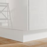 A white FÖRBÄTTRA kitchen plinth. It is sleek, glossy, and sits flush against the wooden floor.