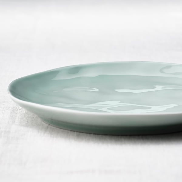 Smooth turquoise plate with iridescent glaze sits on a plain surface, showcasing its minimalist design and durable porcelain texture.