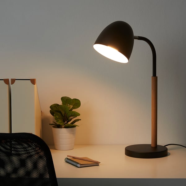 FRANSALG black desk lamp on table with potted plant, notebook, and chair. Adjustable, sleek design, illuminated.