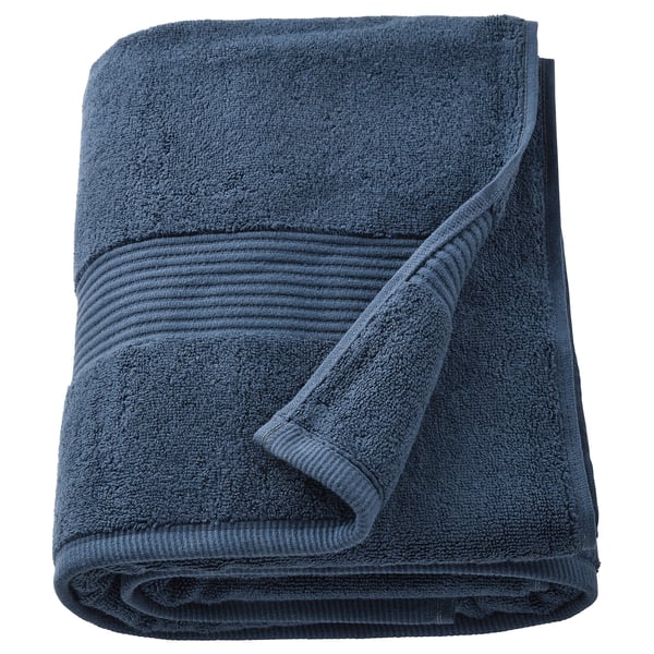 The FREDRIKSJÖN towel is deep blue, thick, and soft with a textured border and rolled shape.
