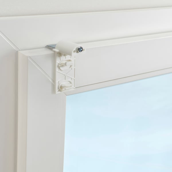 White drill-free bracket mounts on corner of window frame, holding roller blind hardware.
