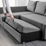 Image depicts a person converting a grey corner sofa into a bed by pulling out the chaise longue section, revealing storage underneath.