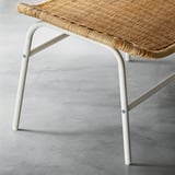 Unique handwoven rattan footstool with sturdy white legs, showcasing natural craftsmanship and durability.