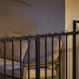 Color-changing outdoor/indoor light strand wrapped around a railing, emitting multiple colored lights.