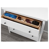 White dresser drawer organizer with three compartments holding folded clothes, a cup, and small items.
