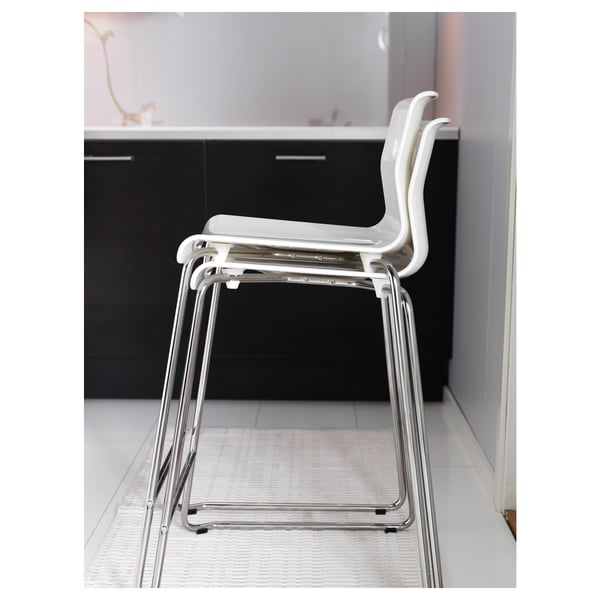 A stack of white, chrome-legged GLENN bar stools. Modern, sleek design in a minimalist setting.