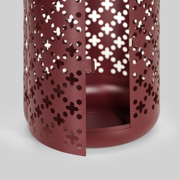 Red metal lantern with intricate cutouts. Durable, warm light design.