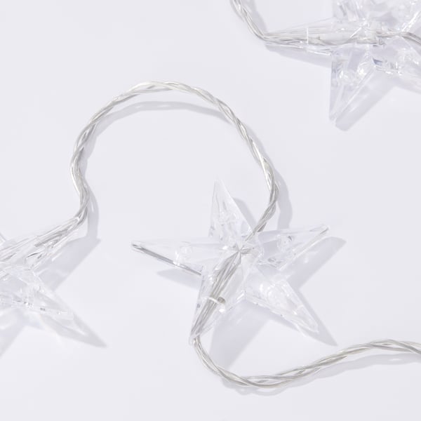 Clear star-shaped string lights with transparent wires; three stars prominent, arranged on a bright white surface.