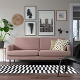 Modern living room with large light pink GRILLSTORP sofa, black & white rug, trendy artwork, and plants. Sofa is medium-sized with clean lines.