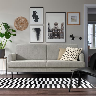 Modern living room with GRILLSTORP gray sofa, polka dot pillows, striped rug, plant, and coffee table.