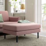 Modern pink fabric sofa with cushions, light grey throw, cozy decor, and large window.