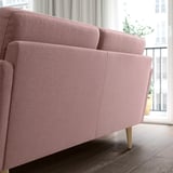 A GRILLSTORP 2-seater sofa in a dusty pink color with visible wooden legs. Its clean design and inviting cushions make it cozy and comfortable.