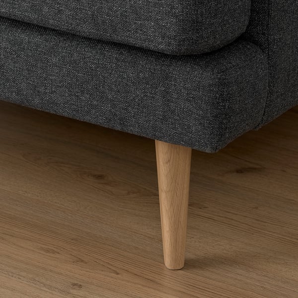 Gray sofa with wooden legs on wooden floor.