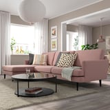 Pink sectional sofa with colorful pillows and glass coffee table in modern living room