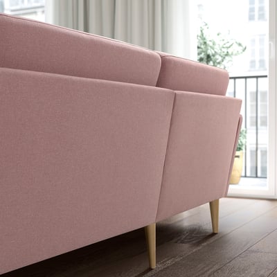 A pink GRILLSTORP 4-seat sofa with wooden legs. Its large and has a clean, inviting design, perfect for a cozy living space.