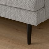 Close-up of sleek, modern sofa with tapered legs. Gray patterned fabric, high-quality design.