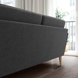 A modern charcoal 4-seat sofa with wooden legs positioned near a large window, showcasing its sleek, inviting design.
