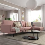 Modern living room with pink sectional, decor pillows, glass table, rug, lamp & curtains. Natural light.