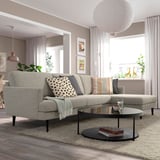Modern living room with GRILLSTORP grey sofa; large cushions, high legs. Centered on rug, with round coffee table, decoratively lit.